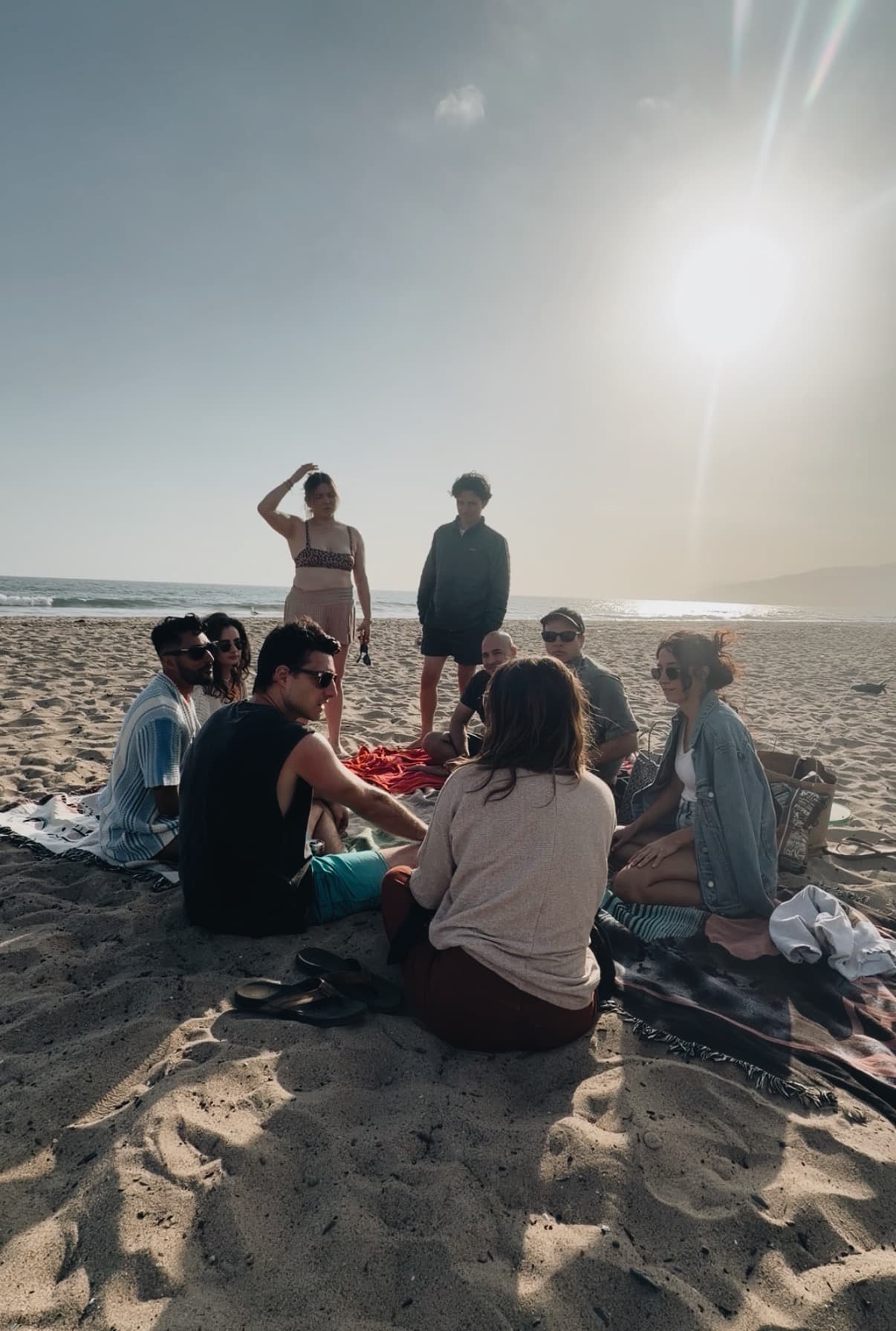 A group of friends hanging out together on the beach at sunset in Los Angeles